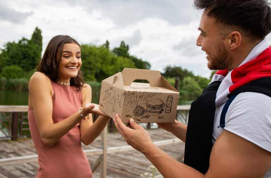A smiling girl getting a box with burger, wondering if fast foods are healthy